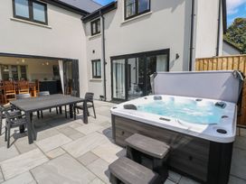 A garden with a hot tub and outdoor dining setup at Ty Landsker in Houghton near Neyland