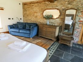 A bedroom with a blue sofa and wooden dresser at Stud Farm House in Bleddfa near Knighton