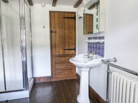 A bathroom with a shower, sink, mirrors, wooden door and shelves at Stud Farm House in Bleddfa near Knighton
