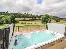A hot tub with a view of a field and trees at Stud Farm House in Bleddfa near Knighton