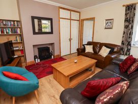 A living room with a television and bookshelves at Godetia Cottage in Seahouses