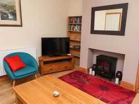 A living room with a television and a bookshelf at Godetia Cottage in Seahouses