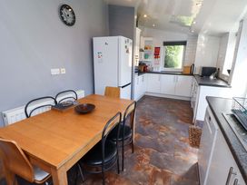 A kitchen with a dining table and refrigerator at Godetia Cottage Seahouses