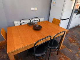 A dining room with a wooden table and chairs at Godetia Cottage in Seahouses