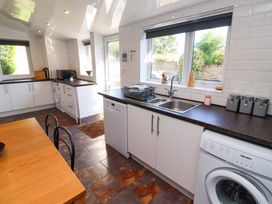A kitchen with appliances and a dining table at Godetia Cottage in Seahouses