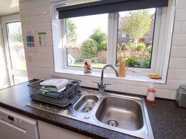 A kitchen with a sink and dish rack at Godetia Cottage in Seahouses