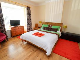 A bedroom with a bed and television at Godetia Cottage in Seahouses
