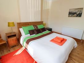 A bedroom with a bed and bedside table at Godetia Cottage in Seahouses