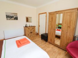 A bedroom with a bed and wardrobe at Godetia Cottage in Seahouses
