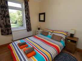 A bedroom with a bed and bedside table at Godetia Cottage Seahouses