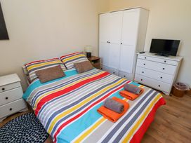 A bedroom with a bed and wardrobe at Godetia Cottage in Seahouses
