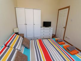 A bedroom with a bed and wardrobe at Godetia Cottage Seahouses
