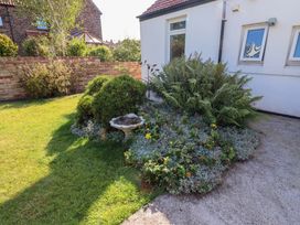 A garden with a flower bed and birdbath at Godetia Cottage Seahouses