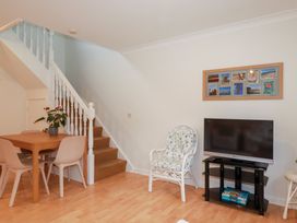 A living room with a dining table and television at Acorns in Falmouth