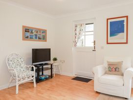 A living room with a television and chairs at Acorns in Falmouth