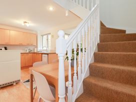 A kitchen with a table, chairs, and stairs at Acorns in Falmouth