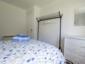 A bedroom with towels on the bed and a rack in the corner at Acorns in Falmouth
