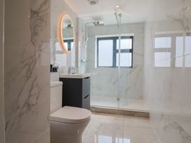 A bathroom with a shower, toilet, sink, and mirror at 1 Mill Green Court Lyme Regis