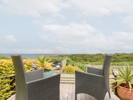 Two chairs on a deck with a view of greenery and ocean at Sea Haven near Primrose Valley