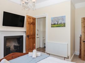 A bedroom with a television mounted on the wall and a door leading to a bathroom at Littleham Court Manor Littleham near Bideford