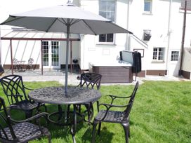 An outdoor seating area with a table and chairs next to a hot tub at Littleham Court Manor Littleham near Bideford