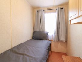 A bedroom with a bed and curtain at Caravan in Northampton