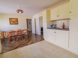 A kitchen with cabinets, a table, and chairs at Ard Na Mara
