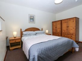 A bedroom with a bed, bedside table and wardrobe at Florence Cottage in Holyhead