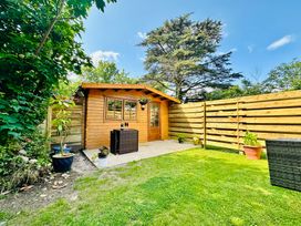 A garden with a wooden shed and patio furniture at Harvey's Lodge in Helston