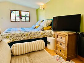 A bedroom with a bed, television, and nightstand at Harvey's Lodge in Helston