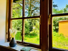 A view of a garden with greenery and a shed from a window at Harvey's Lodge in Helston