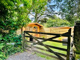 A garden with a wooden gate and a cabin at Harvey's Lodge in Helston