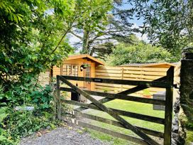 A wooden cabin behind a gate in an outdoor area at Harvey's Lodge, Lowertown, Helston