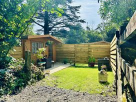 A garden with a wooden cabin and potted plants at Harvey's Lodge in Lowertown, Helston