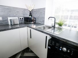 A kitchen with sink, toaster, microwave and washing machine at Lowther House in Whitehaven