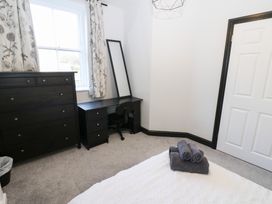 A bedroom with a dresser, desk, and towels in Lowther Apartment Whitehaven
