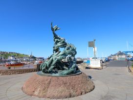 A sculpture in a harbor area with boats and a signpost at Lowther Penthouse in Whitehaven