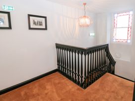 A staircase with a light fixture and photographs on the wall at Lowther Penthouse in Whitehaven