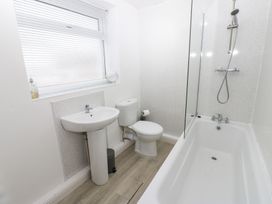 A bathroom with a bath tub, sink, and toilet at Holly House in Waberthwaite