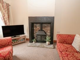 A living room with a fireplace and television at Kirkgate Cottage in Cockermouth