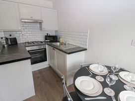 A kitchen with stove, sink, and table settings at Kirkgate Cottage in Cockermouth