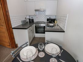A kitchen with appliances and dining setup at Kirkgate Cottage in Cockermouth