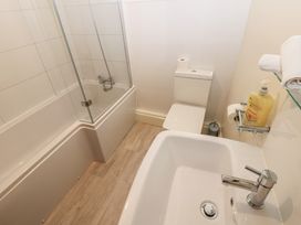 A bathroom with a bath tub, toilet, and sink at Kirkgate Cottage in Cockermouth