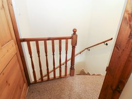 A staircase with a wooden handrail at Kirkgate Cottage in Cockermouth