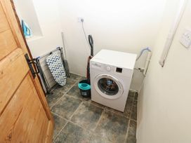 A laundry room with a washing machine and ironing board at Kirkgate Cottage in Cockermouth