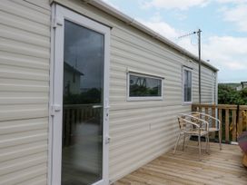A deck with chairs and a doorway at Puffin in St Bees