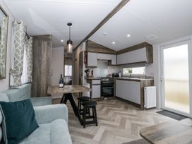 A living room with a kitchen area and dining table at Puffin in St Bees