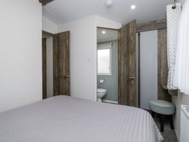 A bedroom with a bed and doors leading to the bathroom at Puffin in St Bees
