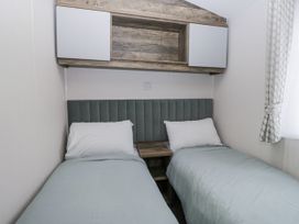 A bedroom with two beds and a shelf at Puffin in St Bees