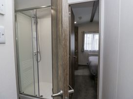 A bathroom with a shower and a view of a bedroom at Puffin in St Bees